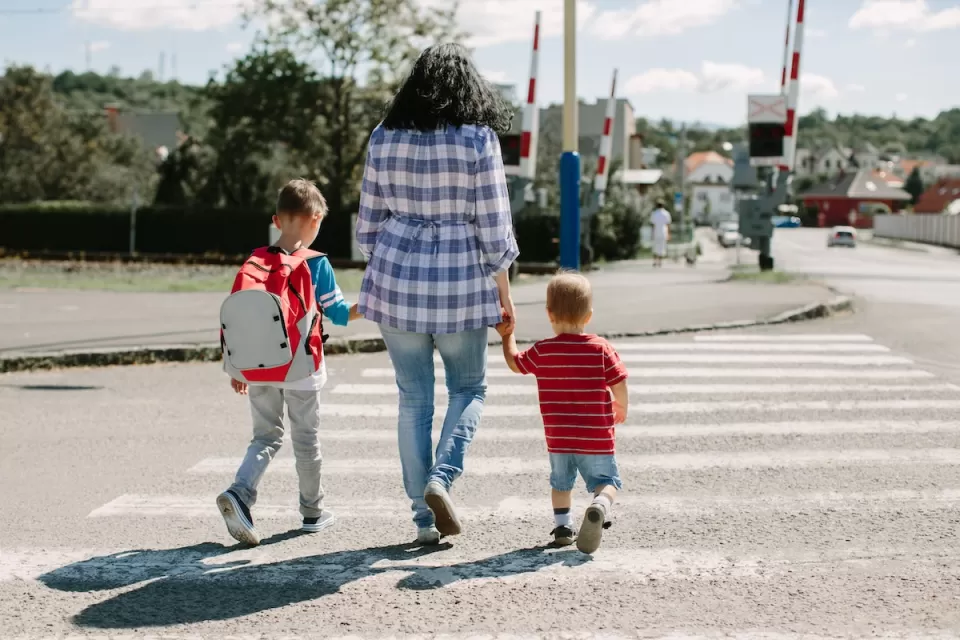 Woman walking two small children across crosswalk.